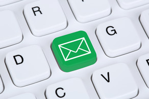 Email Eine weiße Tastatur im Detail. Eine Taste ist grün eingefärbt mit einem weißen Briefumschlag darauf.